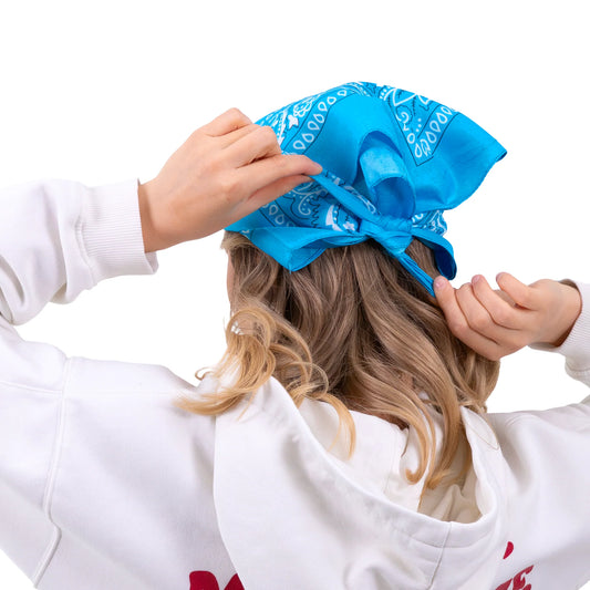 En ljusblå bandana knyts över håret och visar hur den kan stylas som huvudduk bakifrån.