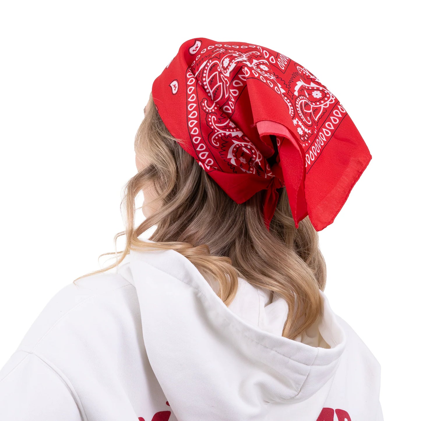 En röd bandana med vitt paisleymönster är knuten över håret och visar hur den kan stylas som huvudduk.