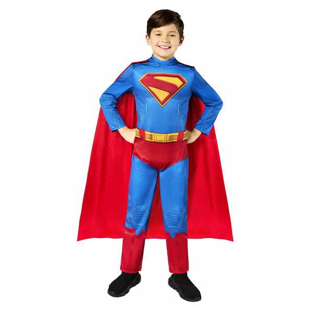 En leende pojke i åldern 5-6 år iklädd en komplett Superman-maskeraddräkt i blått och rött med en stor röd mantel.