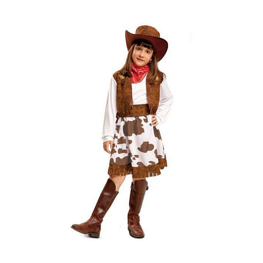 Ett barn i en komplett cowgirl-maskeraddräkt som inkluderar en brun väst, en vit och brun koskinnmönstrad kjol, en röd bandana och en brun cowboyhatt.