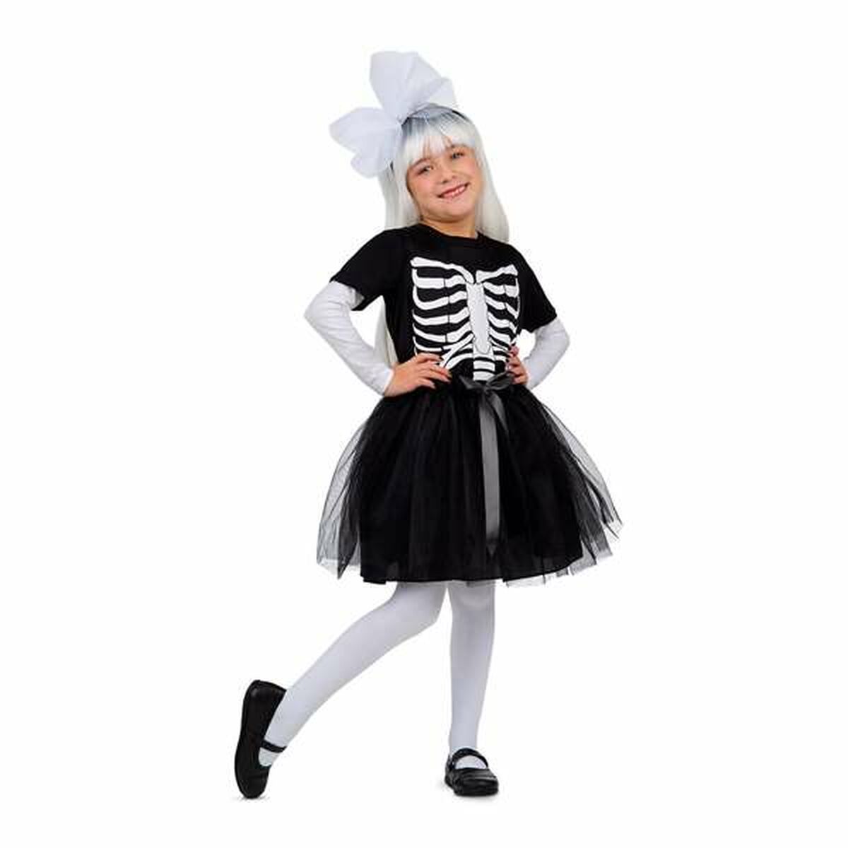 Ett glatt barn i åldern 5-6 år poserar i en svart maskeraddräkt som föreställer ett skelett, bestående av en T-shirt med revbenstryck, en svart tyllkjol och ett vitt hårband med stor rosett.
