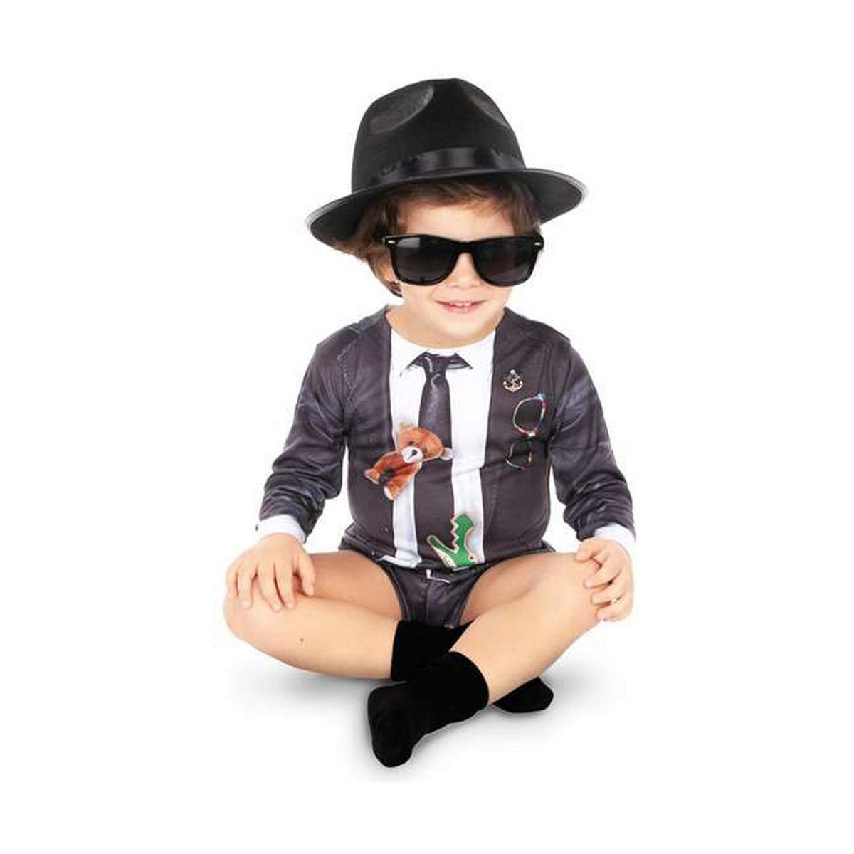 Ett litet barn sitter på golvet iklädd en blues-inspirerad maskeraddräkt med hatt och solglasögon.