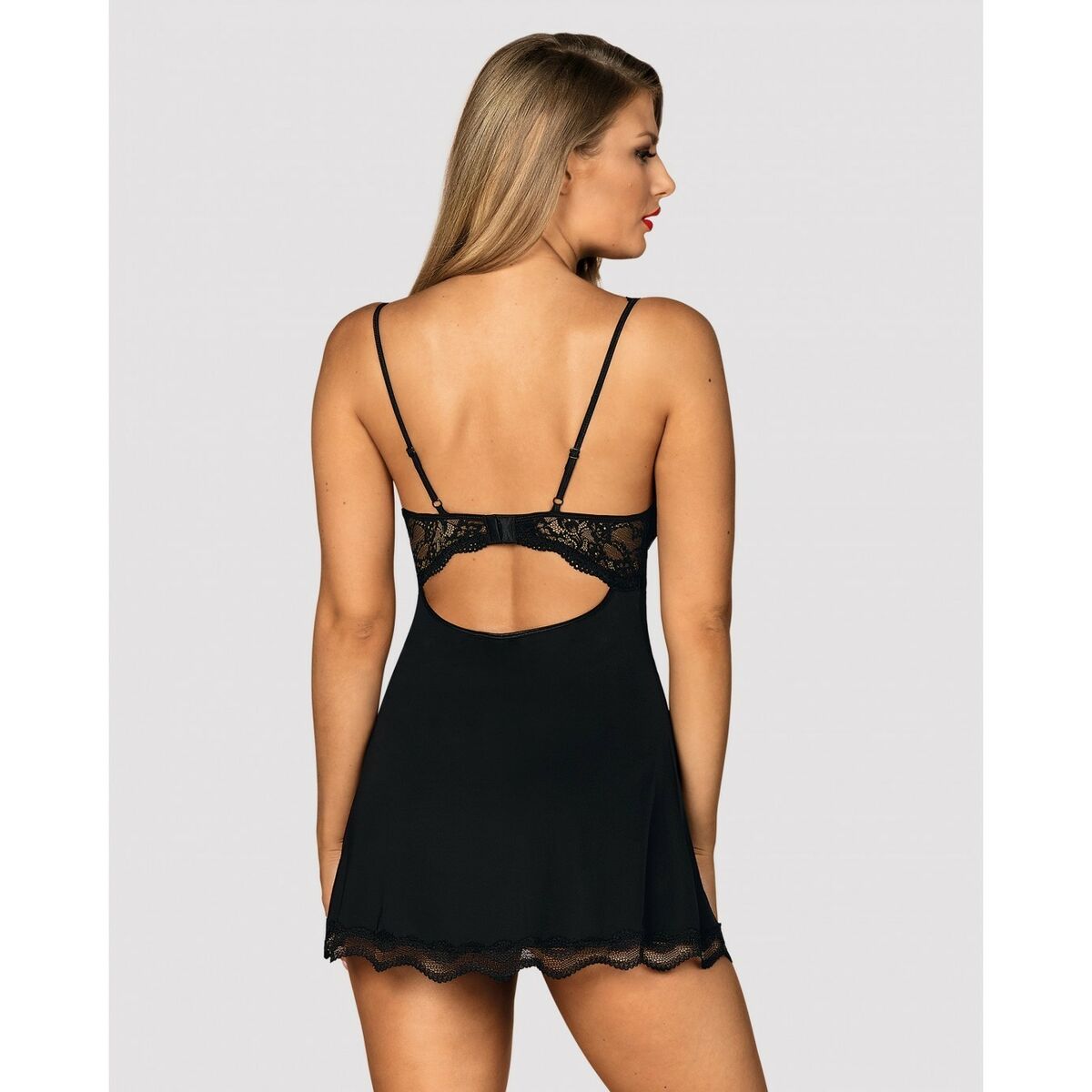 Kvinna sedd bakifrån i en kort svart babydoll med eleganta spetsdetaljer och en vågad utskärning i ryggen.