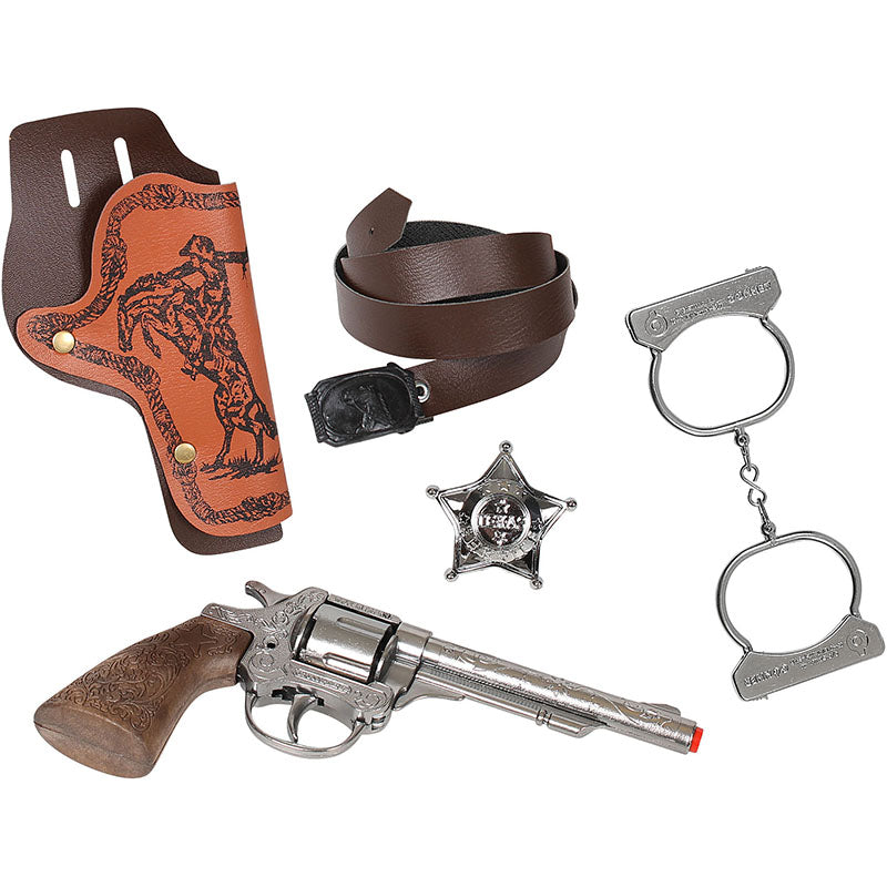 Ett komplett vilda västern leksaksset med silverfärgad revolver i metall och träimitation, brunt hölster, brunt bälte, sheriffstjärna och metallhandklovar fotat mot vit bakgrund.